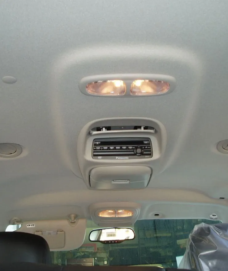 Grey car roof lining with dome lights and an overhead DVD player