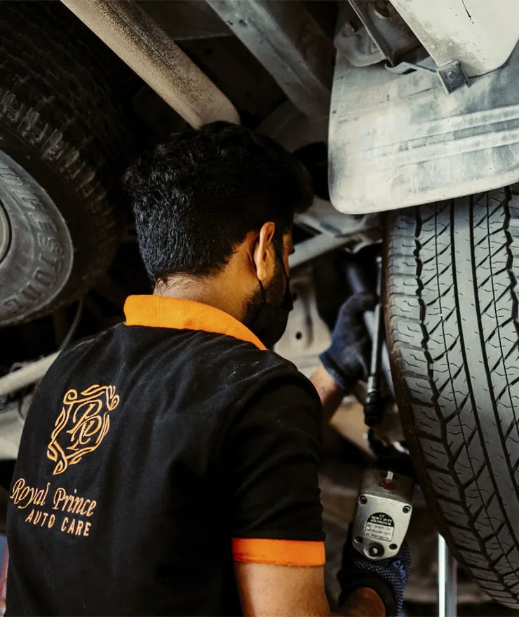A Royal Prince Auto Care technician working under a car